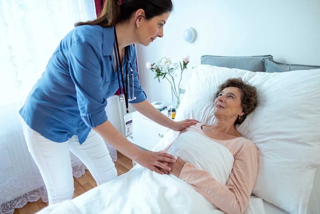 Older adults talking in a bright communal room while a caregiver reviews a daily schedule.