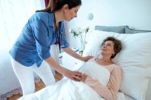 Older adults talking in a bright communal room while a caregiver reviews a daily schedule.